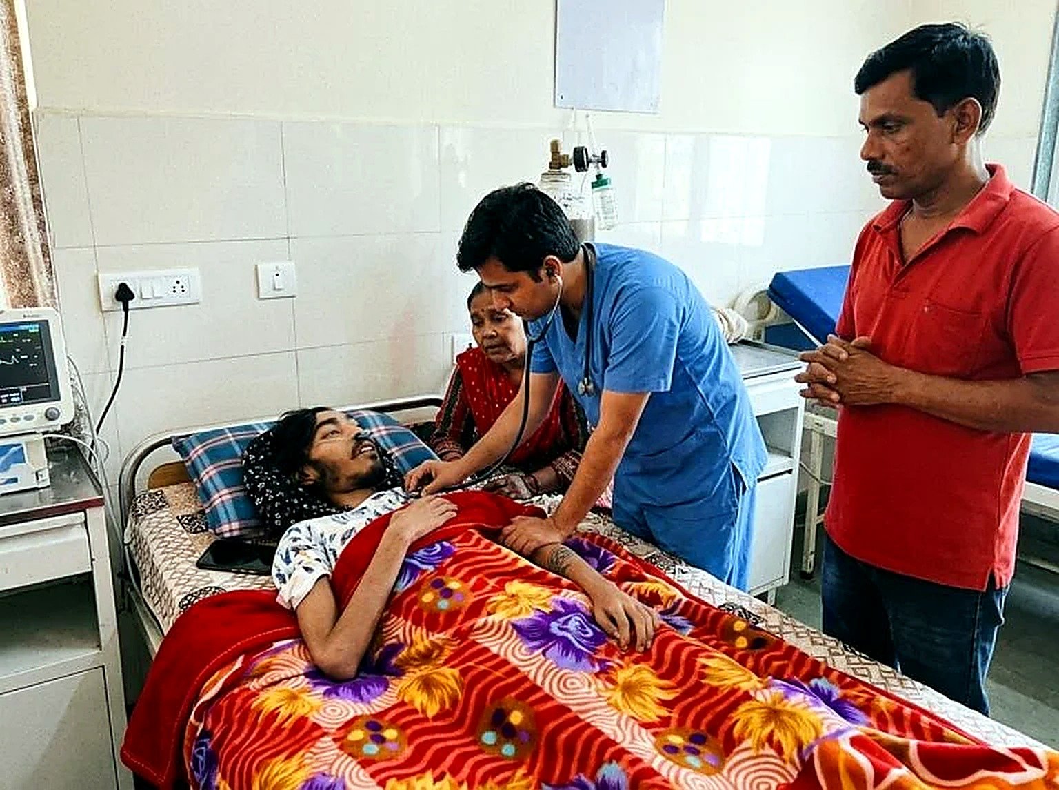 Puran receiving care in a hospital with family nearby